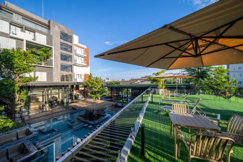 uma piscina com cadeiras, uma mesa e um guarda-sol em Richmann Resort Hotel Hatyai em Ban Kohong