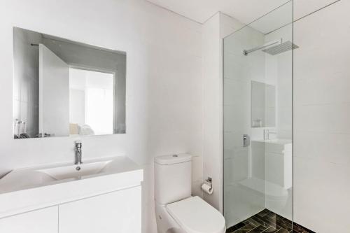 a bathroom with a toilet and a sink and a shower at Shellharbour Lakeview Apartment in Barrack Point