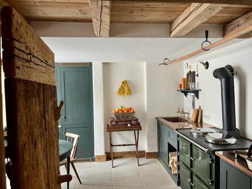 a kitchen with green cabinets and a table with a bowl of fruit at Green Chalet from Centuries ago in Reith bei Kitzbühel