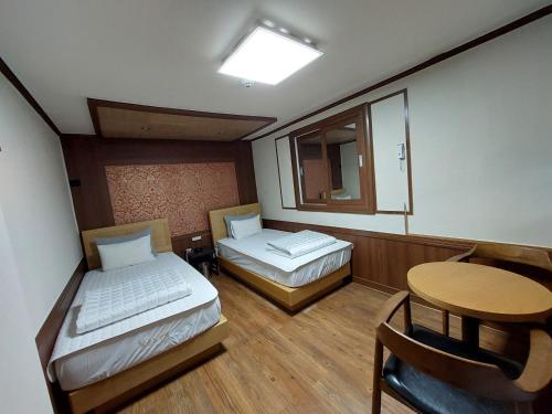 Cette chambre comprend 2 lits, une table et un miroir. dans l'établissement Prince Motel, à Busan