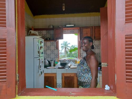 a woman standing in a kitchen with a refrigerator at Casa Mãe - Inn in Principe