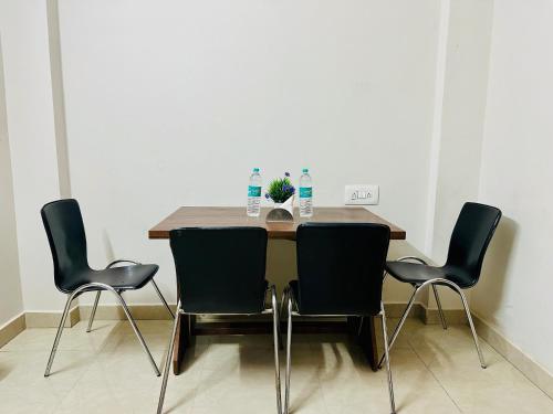a dining room table with four black chairs around it at Orange Corner Hotel, MONTHLY STAY AVAILABLE in Yelahanka