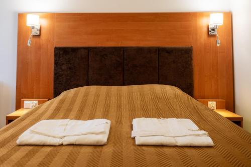 a bed with two towels sitting on top of it at Piastun SPA&Wellness Krynica-Zdrój in Krynica Zdrój