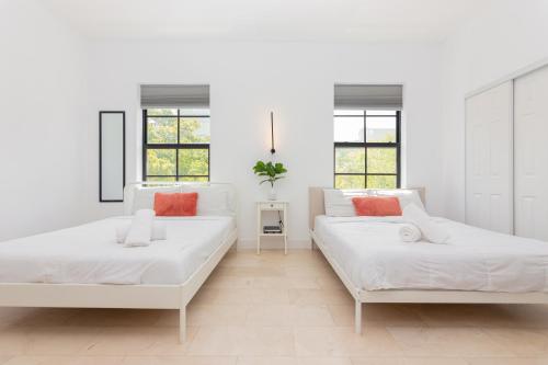 2 łóżka w białym pokoju z oknami w obiekcie Home Miami Downtown - 5 minutes from Wynwood & Port - near Beach w Miami