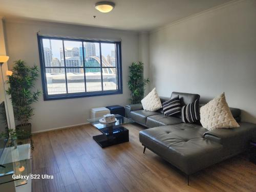 a living room with a leather couch and a window at Beautiful apartment in Pyrmont in Sydney