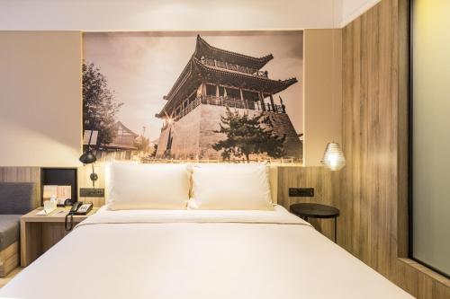 um quarto com uma cama e uma fotografia de um edifício em Atour Hotel Weifang Jinma Road City Hall em Weifang