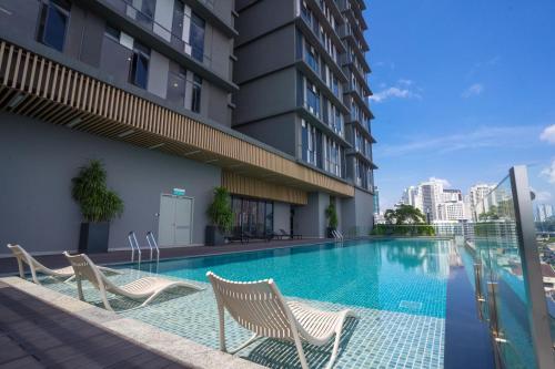 a swimming pool with two chairs and a building at Societe Suites By iHost Global in Kuala Lumpur
