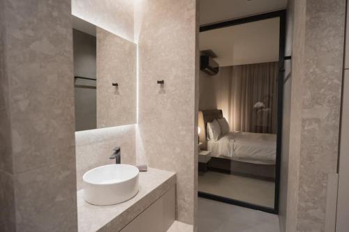 een badkamer met een wastafel, een spiegel en een bed bij ID Residences 203 in Volos