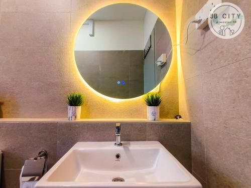 La salle de bains est pourvue d'un lavabo et d'un miroir rond. dans l'établissement Austin JT Homestay by JBcity Home, à Johor Bahru