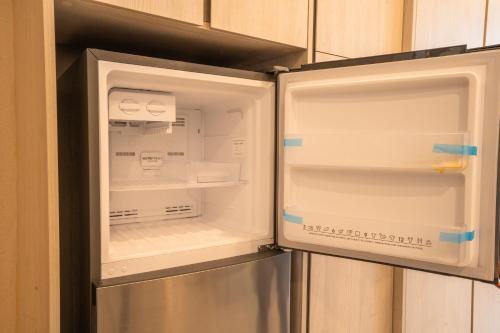 an empty refrigerator with its door open in a kitchen at Societe Suites By iHost Global in Kuala Lumpur