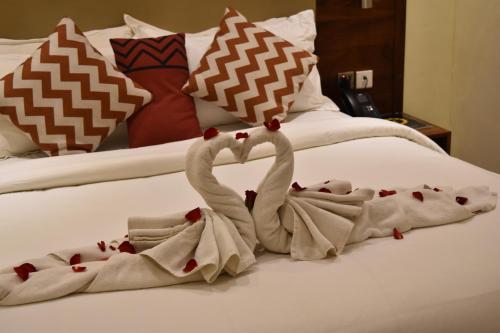 two towels shaped like swans sitting on a bed at Millennium Terrace Hotel in Kampala