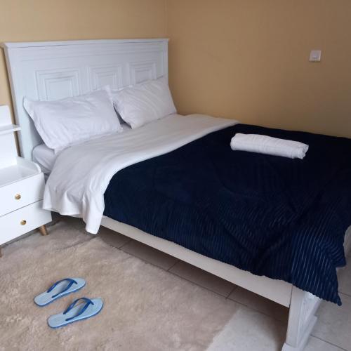 a bed with a blue pair of sandals on the floor at Gateway Homes in Nairobi