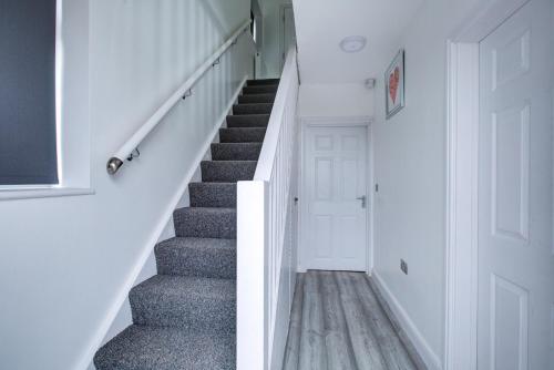 uma escada numa casa com paredes brancas e uma porta branca em CrossVille Homes - 7 bed house, 3 baths, 3 parking em Navestock