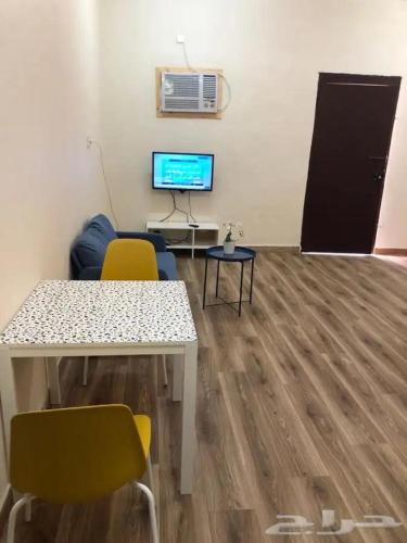 Zimmer mit einem Tisch und Stühlen sowie einem TV in der Unterkunft شقه فاخره in Al Wajh