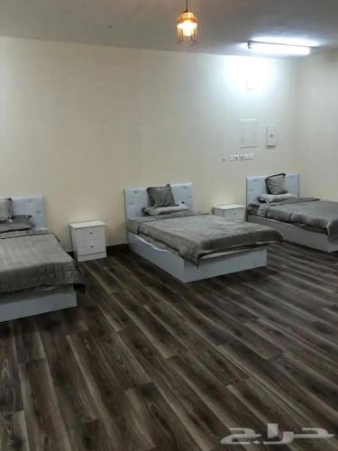 two beds in a white room with wooden floors at شقه فاخره in Al Wajh