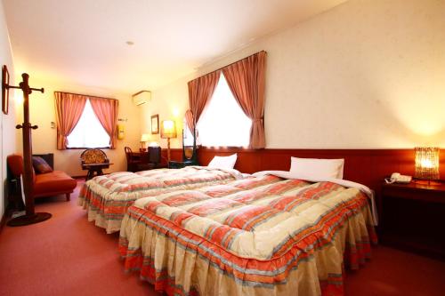 a hotel room with two beds and a chair at IZUNA INN & SPA - the veggie delights in Ito