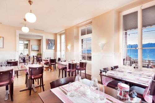 Auberge de la Gare في غراندفو: مطعم بطاولات وكراسي ونوافذ