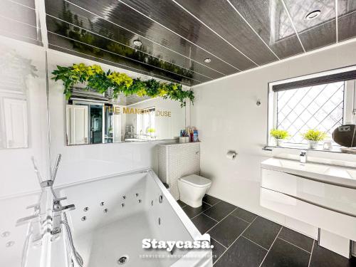 uma casa de banho com uma banheira, um lavatório e um WC. em Beautiful Detached Villa - Jacuzzi Bath - Parking em Manchester