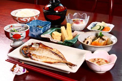 a table with a plate of fish and other foods at IZUNA INN & SPA - the veggie delights in Ito