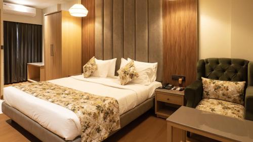 um quarto de hotel com uma cama e uma cadeira em The Cindrella Hotel em Siliguri