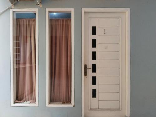 due porte bianche in una stanza con tende rosa di SMAN House powered by Cocotel a Bekasi