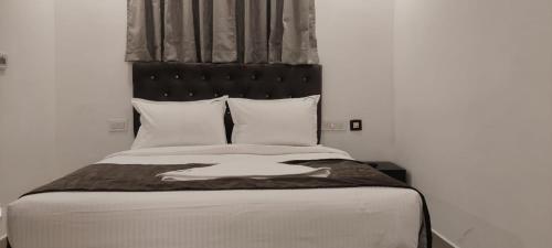 a bed with a black headboard and white pillows at Earth Inn in Chennai