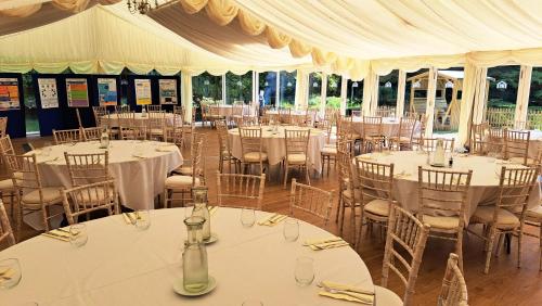 a banquet hall with tables and chairs with white tablecloths at The Coach House at Missenden Abbey in Great Missenden