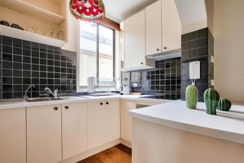 uma cozinha com armários brancos e azulejos pretos em 2 Bedroom Apartment Newtown Near to Shops 2 em Sydney