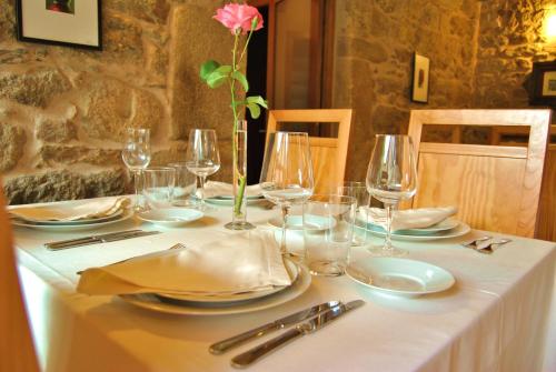 a table with plates and glasses and a flower on it at Torres de Moreda in A Estrada