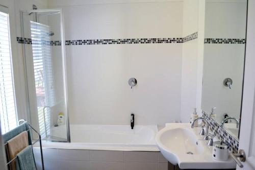 uma casa de banho branca com um lavatório e um chuveiro em BLAIRGOWRIE BEACH SHACK..bay beach location em Blairgowrie