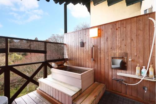 a bathroom with a sink on a wooden wall at IZUNA INN & SPA - the veggie delights in Ito
