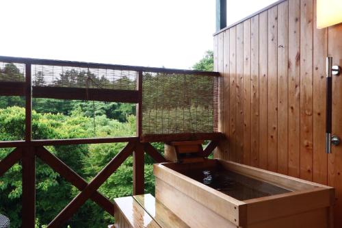 a bath tub in a room with a large window at IZUNA INN & SPA - the veggie delights in Ito