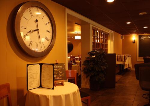 a clock on the wall of a restaurant with a table at Macaluso's at the Lantern Lodge in Jim Thorpe