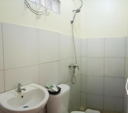 Baño blanco con lavabo y aseo en De Plaza Hotel, en Surabaya
