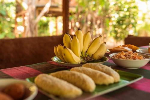 a table topped with plates of bananas and bread at Sigiri Aliya Tree house in Sigiriya