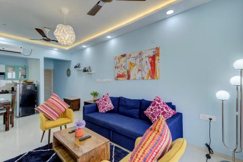 sala de estar con sofá azul y mesa en Coral BnB Premium 2 BHK Apartment - 5 km from Dabolim Airport, en Vasco Da Gama