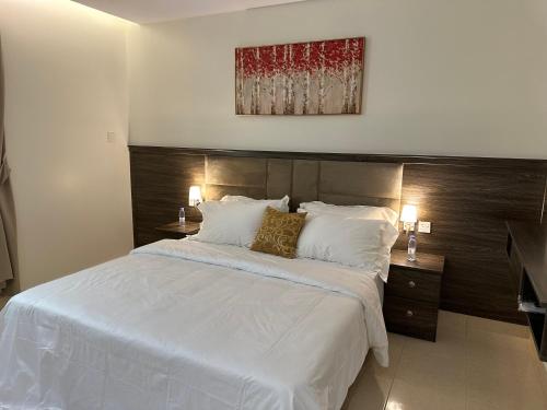 1 dormitorio con 1 cama grande con sábanas y almohadas blancas en استديو أنيق بدخول ذاتي en Al Kharj