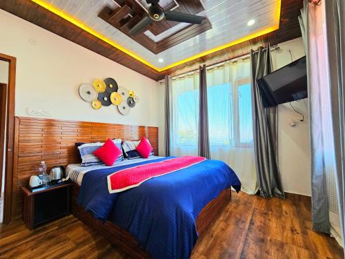 a bedroom with a bed with red pillows and a tv at THE TULIP BIR in Bīr