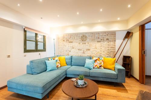 een woonkamer met een blauwe bank en een tafel bij Lito's Central Gem - Cozy Dream Getaway in Kalamata
