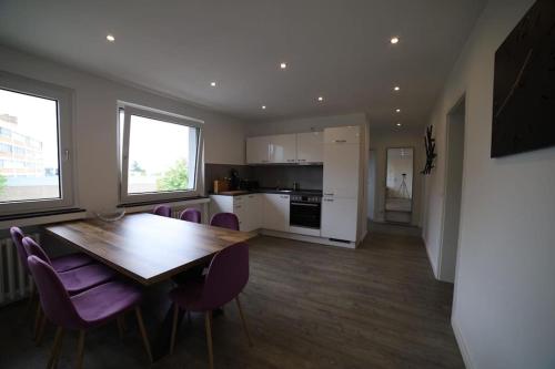 a kitchen and dining room with a wooden table and purple chairs at Designer-Apartment near Düsseldorf+Cologne (Apt.3) in Neuss