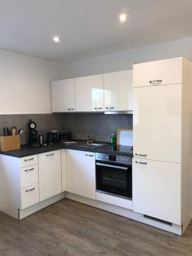 a kitchen with white cabinets and a black oven at Designer-Apartment near Düsseldorf+Cologne (Apt.3) in Neuss