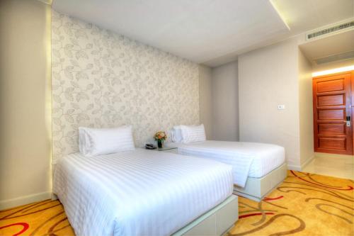 two beds in a room with white sheets at One One Bangkok in Bangkok