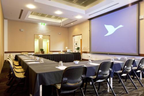 a meeting room with tables and chairs and a projection screen at Novotel Tainui Hamilton in Hamilton