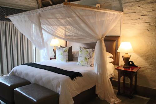 a bedroom with a canopy bed with white sheets and pillows at Entabeni Mountain Lodges in Golders Green