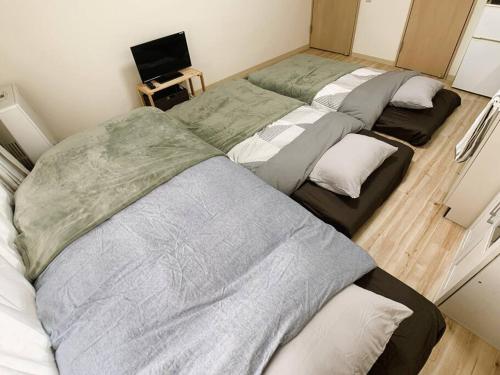 three beds are lined up in a room at 新三条Home 402 in Asahikawa