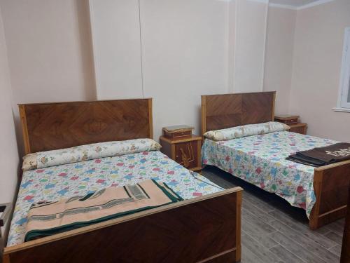 two beds in a room with two tables at Happy Transit in Cairo