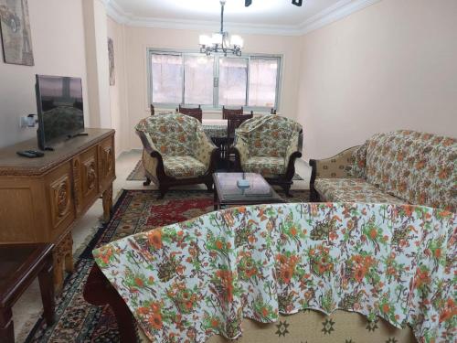 uma sala de estar com um sofá e cadeiras e uma televisão em Happy Transit no Cairo