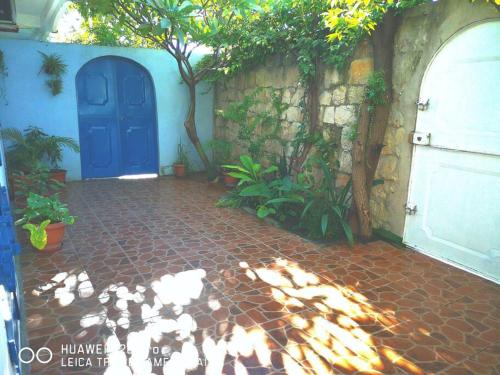 una puerta azul en una casa con un patio de ladrillo en La villa flamboyant, en Mahajanga