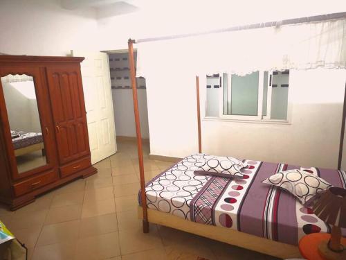 a bedroom with a bed and a dresser at La villa flamboyant in Mahajanga