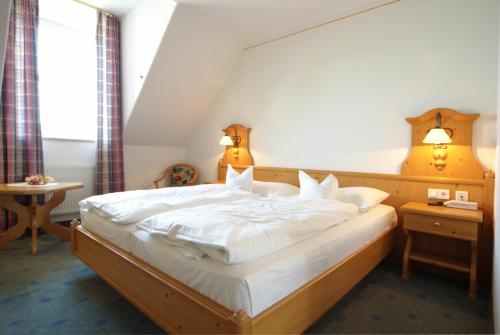 a bedroom with a large bed with white sheets at Fichtelgebirgshof in Himmelkron